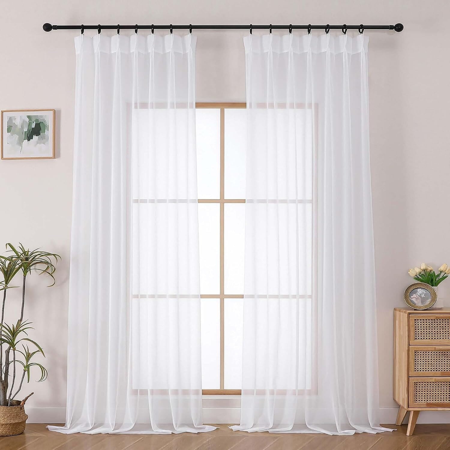 Two long white sheer curtains suspended from a visibly pinch-pleated header